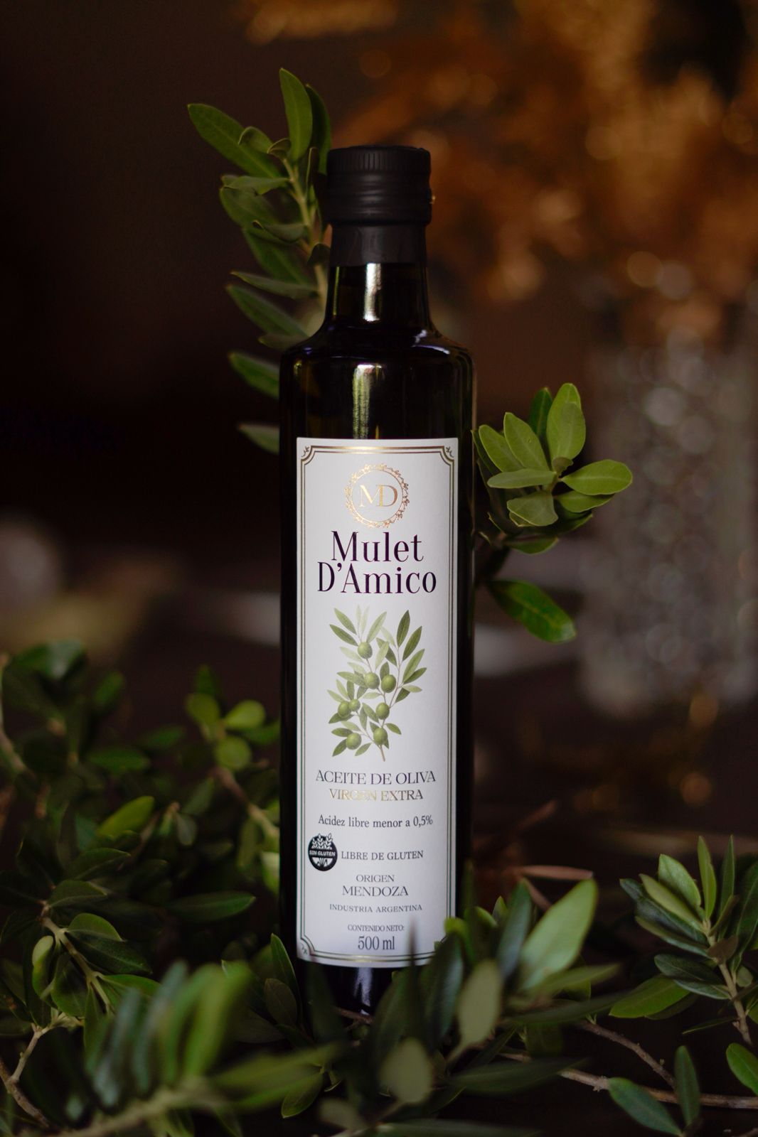 Botella de aceite de oliva Mulet D'Amico entre ramas de olivo