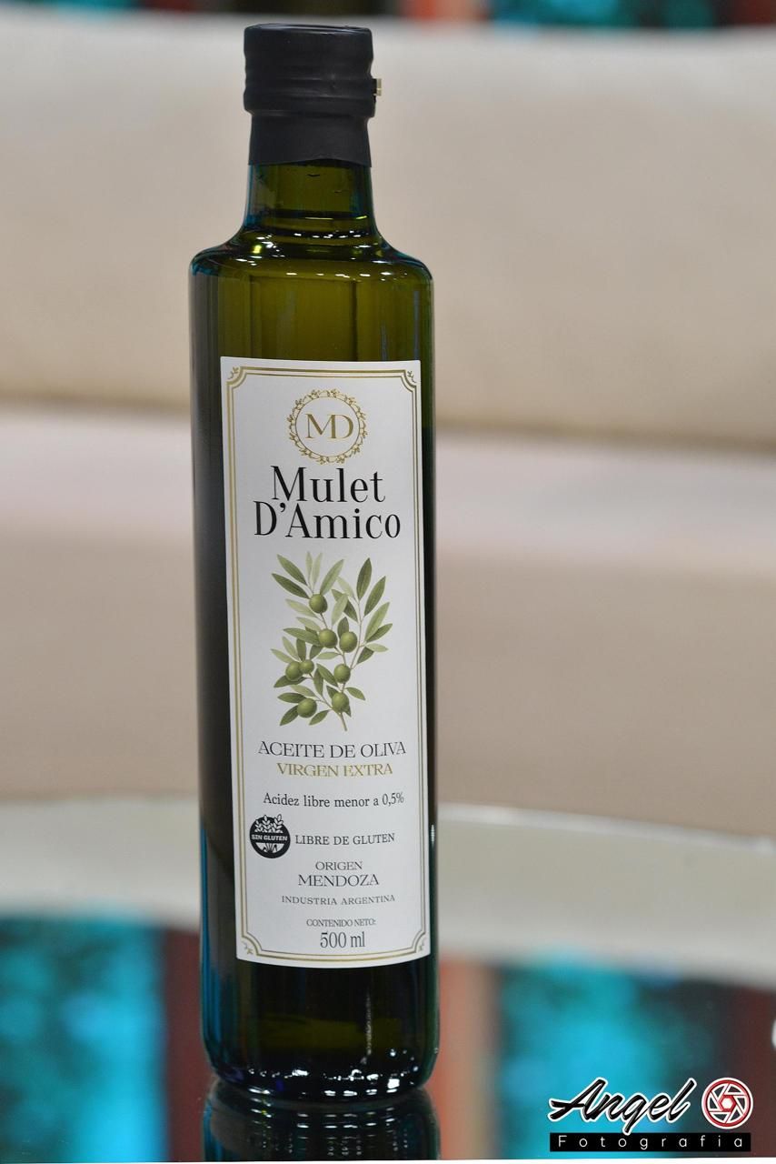 Botella de aceite de oliva Mulet D'Amico sobre una mesa, junto a aceitunas y pan